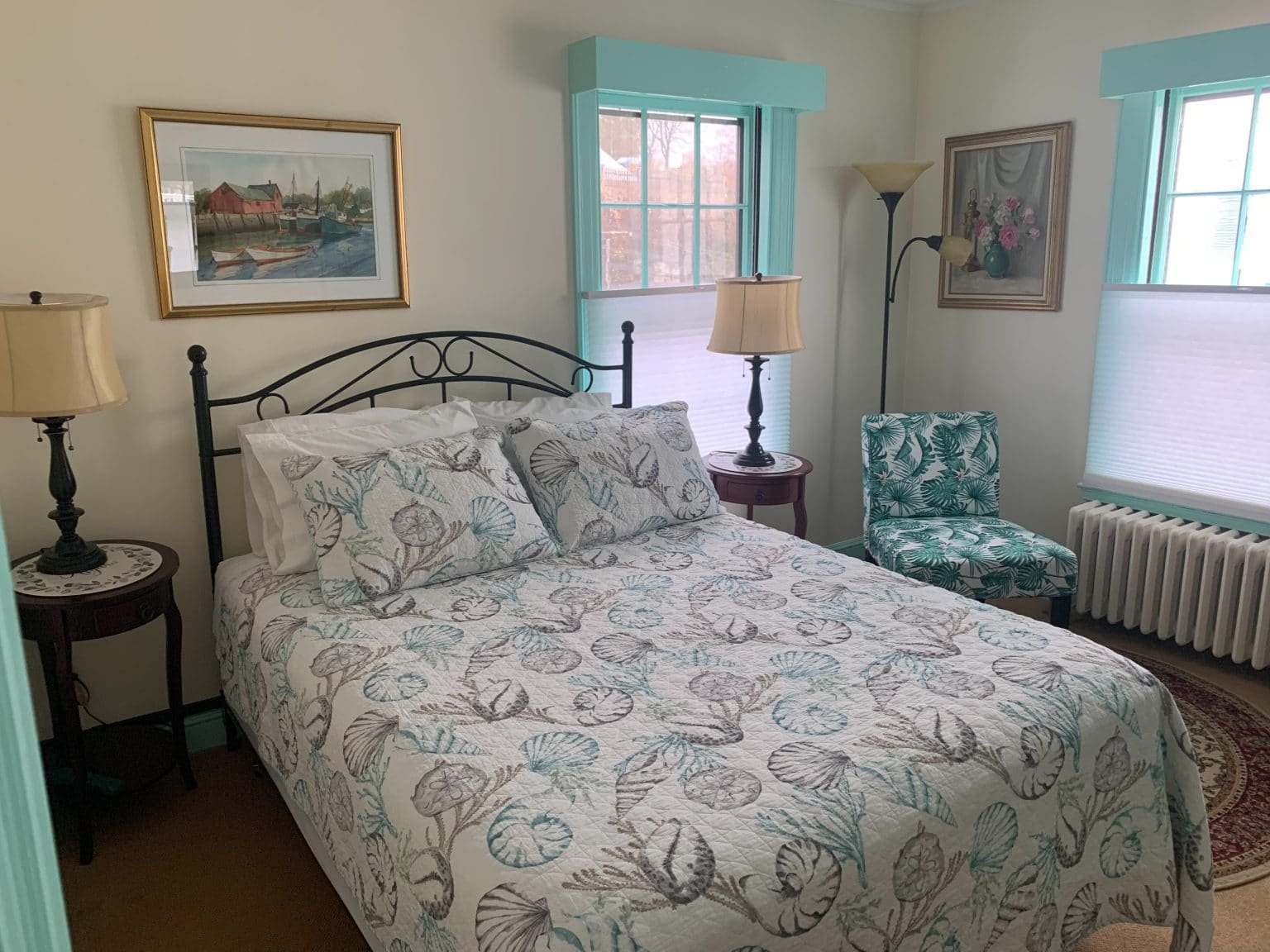 A guest room at the Harborview Inn, bed made, harbour painting above it